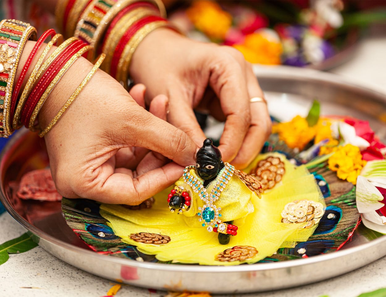 A woman doing the ritual of bathing little lord krishna idol during the festival of Janmashtami