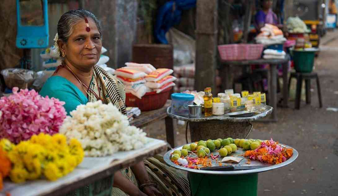 An elderly woman selling flowers in a south Indian street